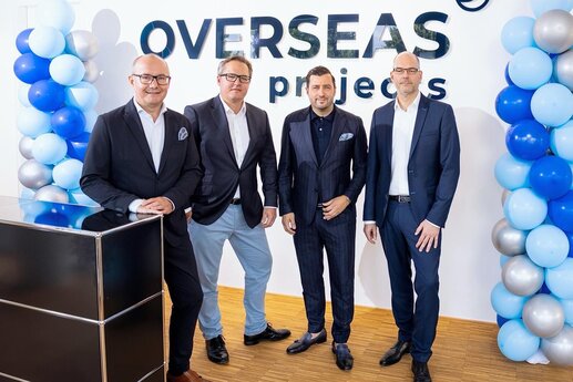 (Von links:) Hans-Bernd Effing (Geschäftsführer der Overseas Projects), Dominik Lucius (CFO der FMS), Navid Thielemann (CEO der ThielemannGroup) und Heiko Voigt (CEO der FMS) vor einer Stellwand mit dem Overseas Projects-Schriftzug und vor zwei mit Luftballons geschmückten Säulen
