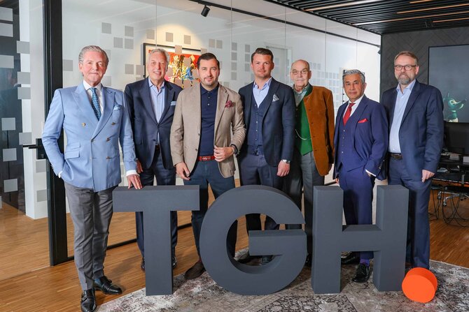 Gruppenfoto des fünfköpfigen Beirats und des Management-Teams der ThielemanGroup mit den hüfthohen Buchstaben TGH davor
