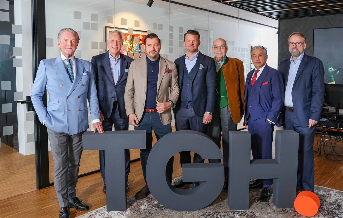 Gruppenfoto des fünfköpfigen Beirats und des Management-Teams der ThielemanGroup mit den hüfthohen Buchstaben TGH davor